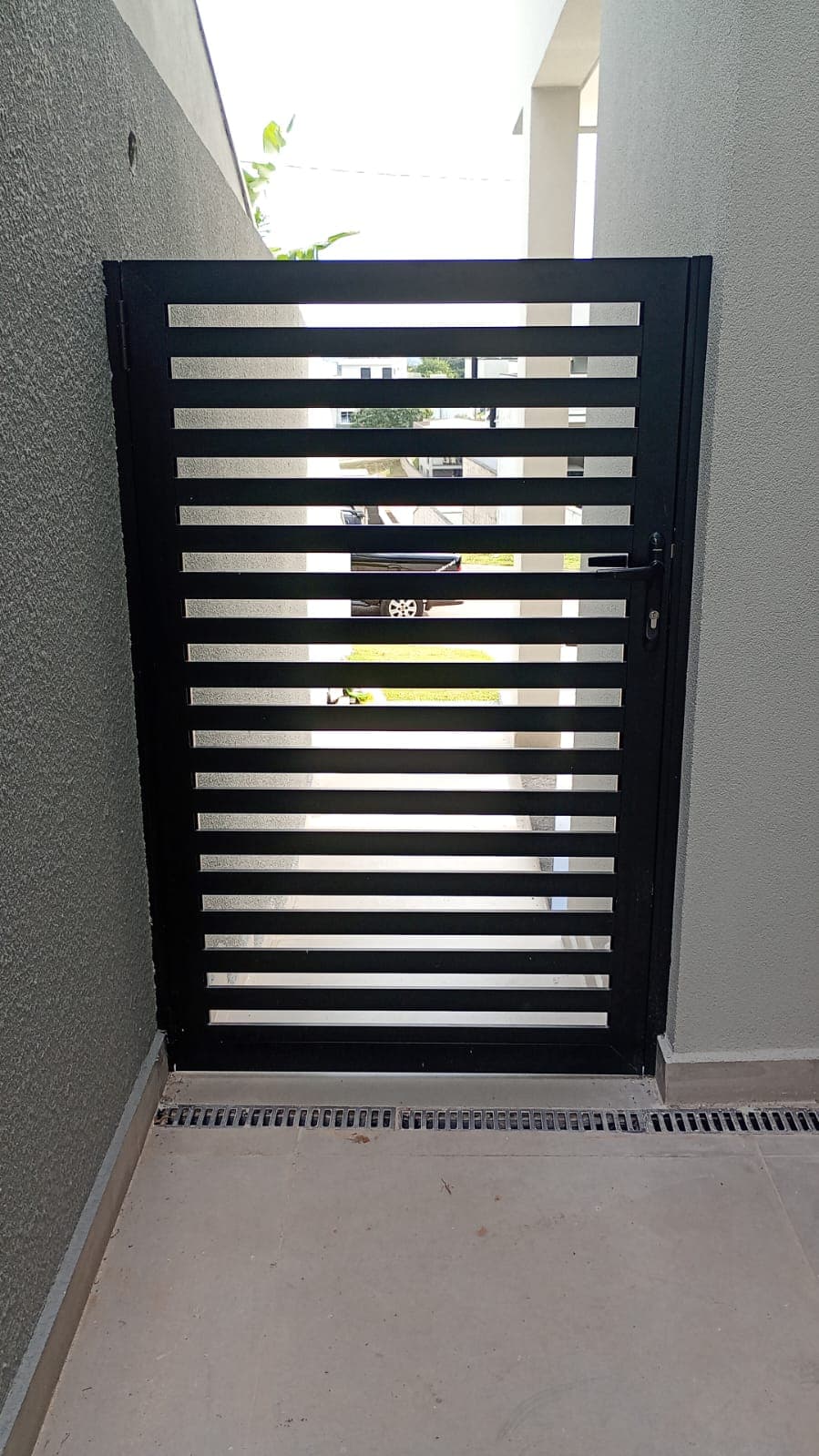Portão lateral em alumínio ripado preto em corredor externo